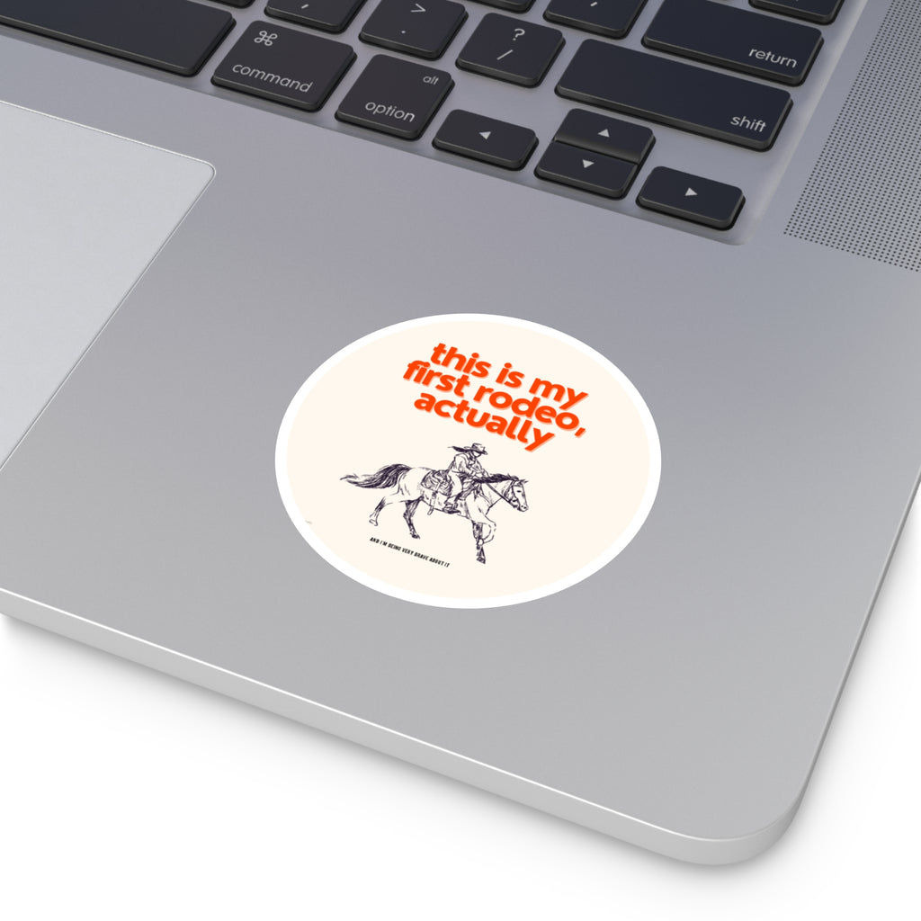 Laptop with a sticker featuring a cowboy and text 'this is my first rodeo, actually' on a white background.
