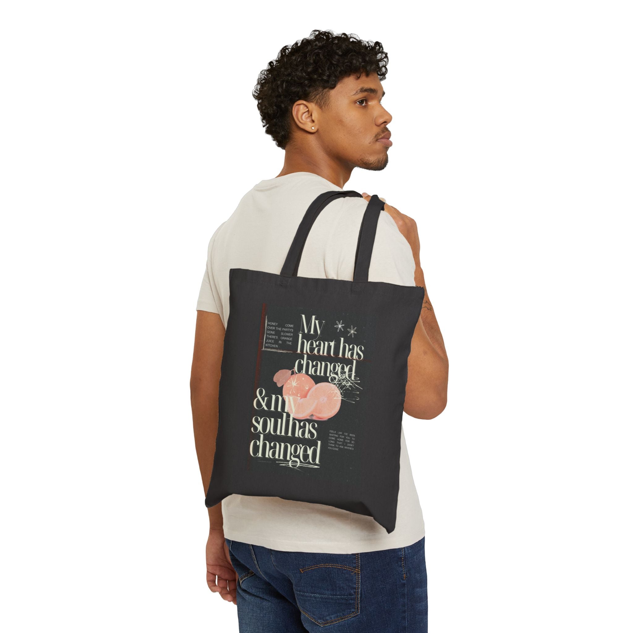 Person wearing a black tote bag with a colorful fruit design with text.