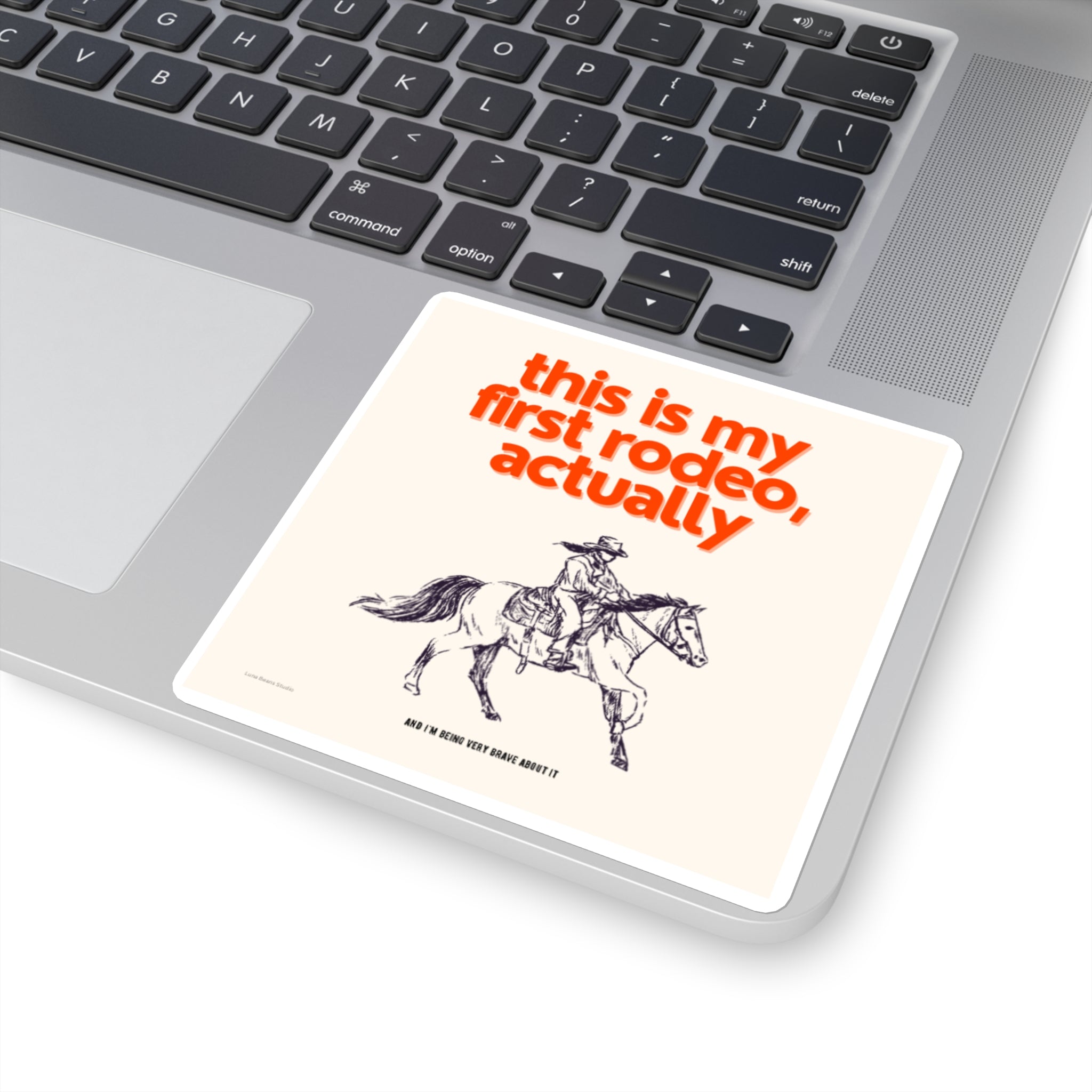 Sticker with a cowboy design and text reading "this is my first rodeo, actually" on a laptop