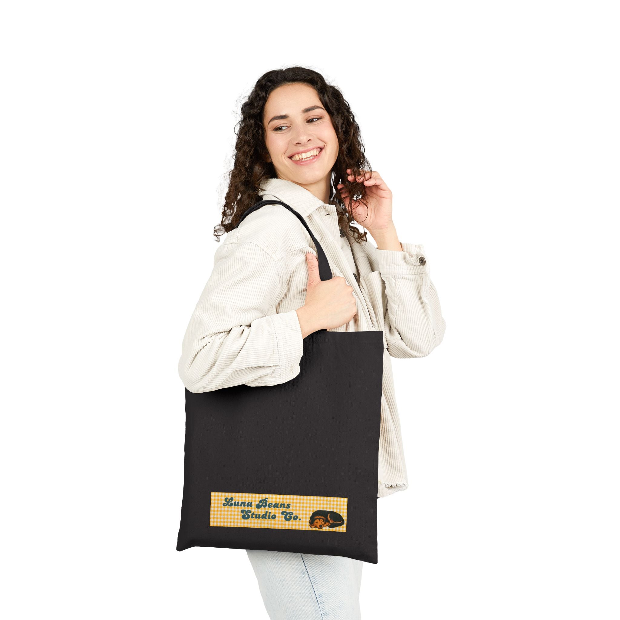 Woman holding a black tote bag with a logo on a white background